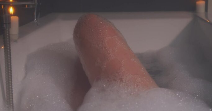 Sexy woman legs and feets in a romantic tub with bubbles and candles