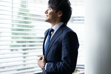 窓を見つめる若い日本人ビジネスマン