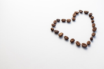 Heart shape created with coffee beans isolated on a white background.