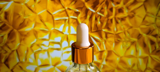 Anti-aging serum in a glass bottle with a dropper on a bright yellow glass background. Liquid serum for the face with collagen and peptides. Skin care essence for beautiful healthy skin. A mock-up of