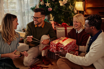 Four smiling friends wrapping Christmas gifts