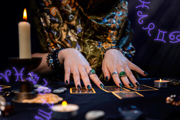 Cartomancy. A fortune teller reads Tarot cards. On the table are candles. Hands close up. Zodiac circles are located in the corners of the image. The concept of divination, astrology and esotericism