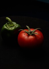 tomato and green peppers on black background