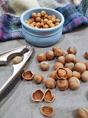 inshell hazelnuts lie on the table next to the tongs for chopping, peeled hazelnuts in a plate