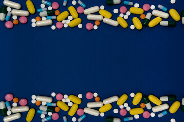 Excessive intake of drugs or vitamins. Blue background with a variety of vitamins or medications