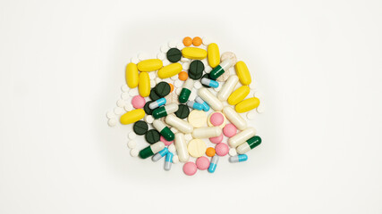 Variety of medicines and capsules in a woman's palm on a blue background. The concept of consuming a large number of drugs