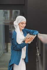 Smiling asian girl student professional employee holding tablet and sit at outdoor park, happy woman studying e learning online software using technology app for work education