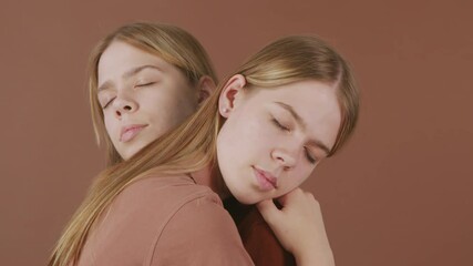 PAN shot of identical twin sisters hugging against brown background - Powered by Adobe