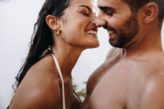 Smiling couple flirting under an outdoor shower