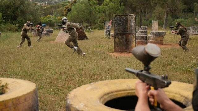  Dynamic paintball battle, players jumping and aiming with guns outdoors