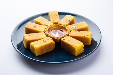 Mysore Pak and diwali diya or clay lamp decorated in a plate - Happy Diwali Greeting