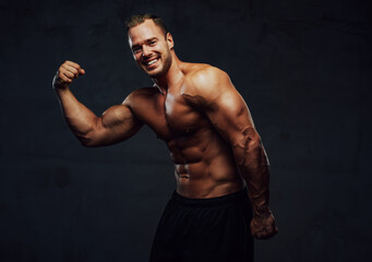 Fototapeta na wymiar Guy with naked torso and huge biceps posing in studio