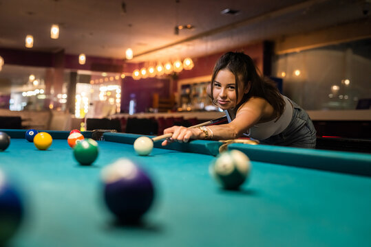 cheerful young woman playing billiard in pub - Powered by Adobe