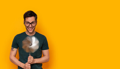 Young happy man with big glasses holding a wind wheel
