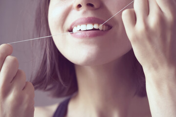 Girl flosses her teeth in the morning.