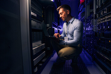 Employee checking hardware equipment in server room - obrazy, fototapety, plakaty