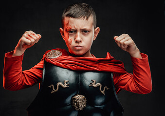 Brave little legionary in dark armou with red cloak in dark background