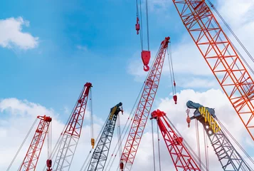 Fotobehang Crawler crane against blue sky and white clouds. Real estate industry. Red crawler crane use reel lift up equipment in construction site. Crane for rent. Crane dealership for construction business. © Artinun