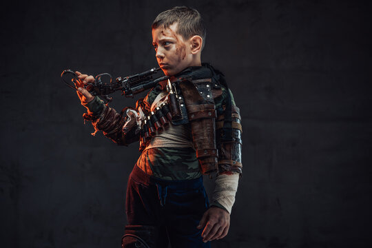 Armoured preschool boy with gun on his shoulder in dark background