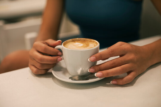 Young woman with manicured nails having coffee at cafe