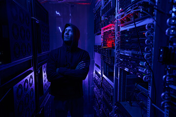 Serious data center intruder examining network equipment - obrazy, fototapety, plakaty