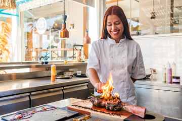 Smiling female chef smoking steak in kitchen