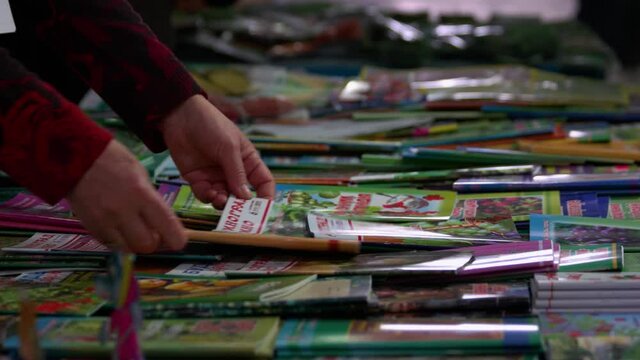 Vendors hands sorting through pile of magazines.