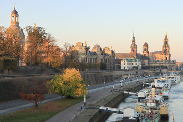 Obraz premium Herbstmorgen am Dresdner Elbufer; Brühlsche Terrasse mit den architektonischen Wahrzeichen der Stadt, unten am Terrassenufer die Flotte der historischen Raddampfer