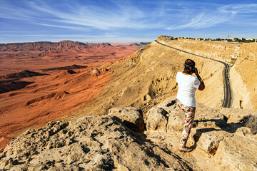 Woman photographing on a steep cliff