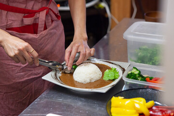カレーライスの盛り付けをする女性料理人