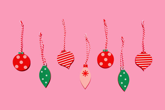 Studio shot of row of wooden Christmas decorations flat laid against pink background