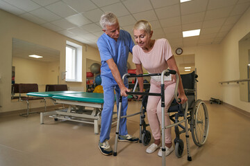 Caucasian female uses mobility walker in rehab center
