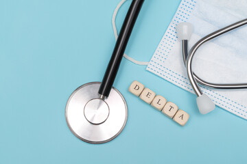 Covid-19 delta word on wooden cubes. Covid-19 delta word with face mask and stethoscope on blue...