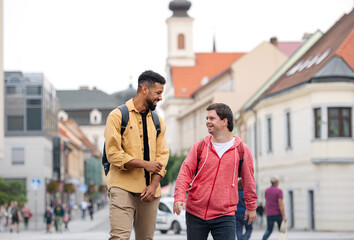 Young man with Down syndrome and his mentoring friend walking and laughing outdoors