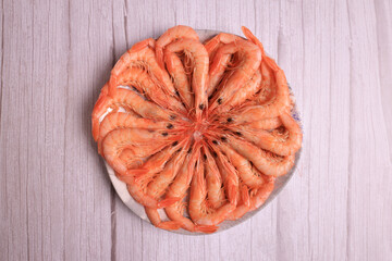 Portion of cooked white prawns from Huelva on gray light wooden background
