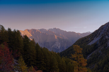 Autumnal colors at the earli morning on the Graian Alps, with the sun illuminating the crests of the valleys.