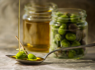 Aceite de oliva con olivas en cuchara y cayendo chorro de aove.