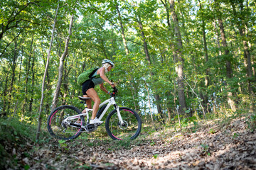 Fototapeta na wymiar Low angle view of active senior woman biker cycling outdoors in forest.