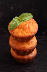 Stacked cheese muffins on a black background decorated with basil