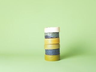 Six natural handmade round soaps in the form of the tower opposite the green background, in the...