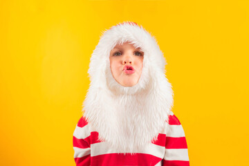 Funny child toddler in a Santa hat with red gift , yellow background. Holidays, Traditions, Christmas concept.