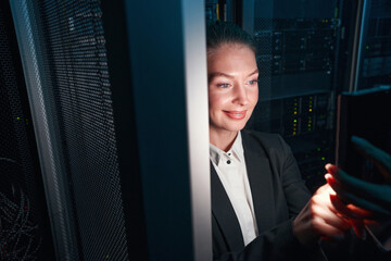 Cheerful woman network engineer working in server room