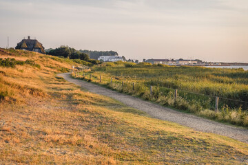 Germany, Schleswig-Holstein, Sylt, Munkmarsch, Countryside dirt road with village in background