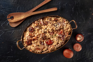 Risotto ai funghi, mushroom rice, overhead flat lay shot on a black slate background