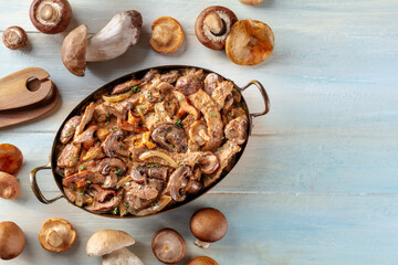 Beef stroganoff, mushroom and meat ragout with cream sauce, traditional dish of Russian cuisine, shot from the top on a rustic wooden background