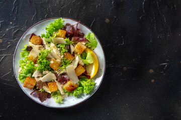 Chicken Caesar salad, overhead shot on a black background with a place for text