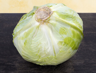 White cabbage head with cabbage stalk up, on dark surface