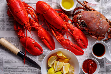 Boiled red Lobsters, crab and crawfish on newspaper background. Seafood with copy space