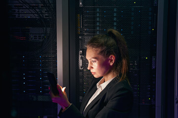 Woman engineer working in data center by server storage racks
