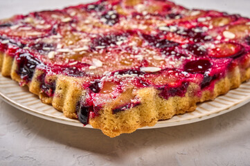 Macro tart or pie with plums on plate on light wooden background. Selective focus